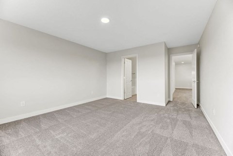 A spacious room with a carpeted floor and white walls.