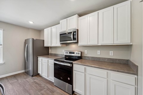 A kitchen with white cabinets and a stainless steel refrigerator.