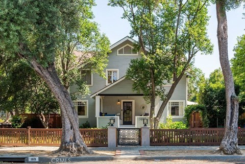 A house with a white fence and a tree in front.