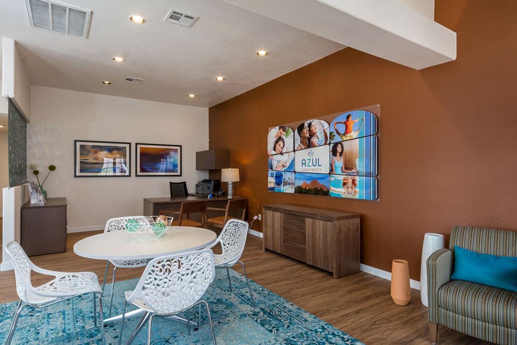 A living room with a white table and chairs, a blue rug, and a brown cabinet.