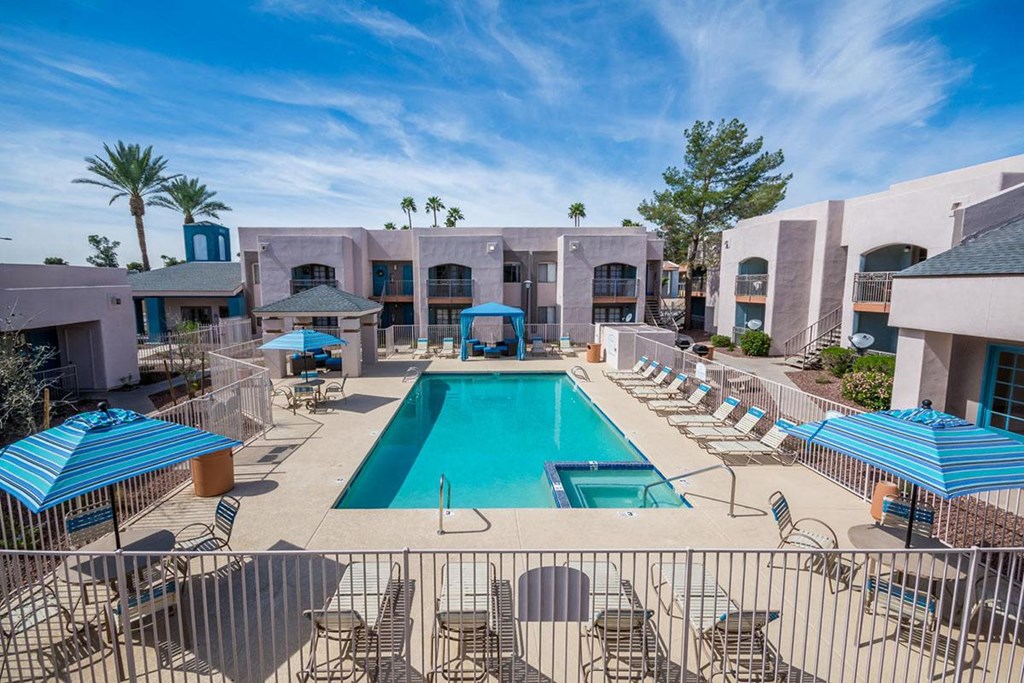 A large swimming pool surrounded by lounge chairs and umbrellas.