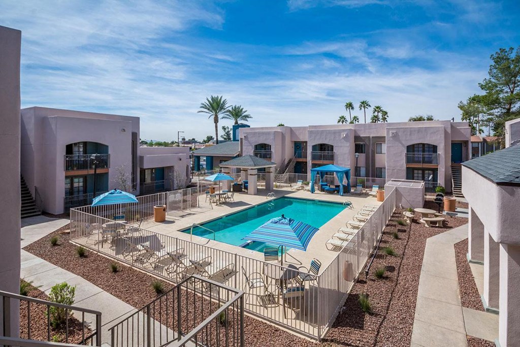 A pool surrounded by a fence and chairs.