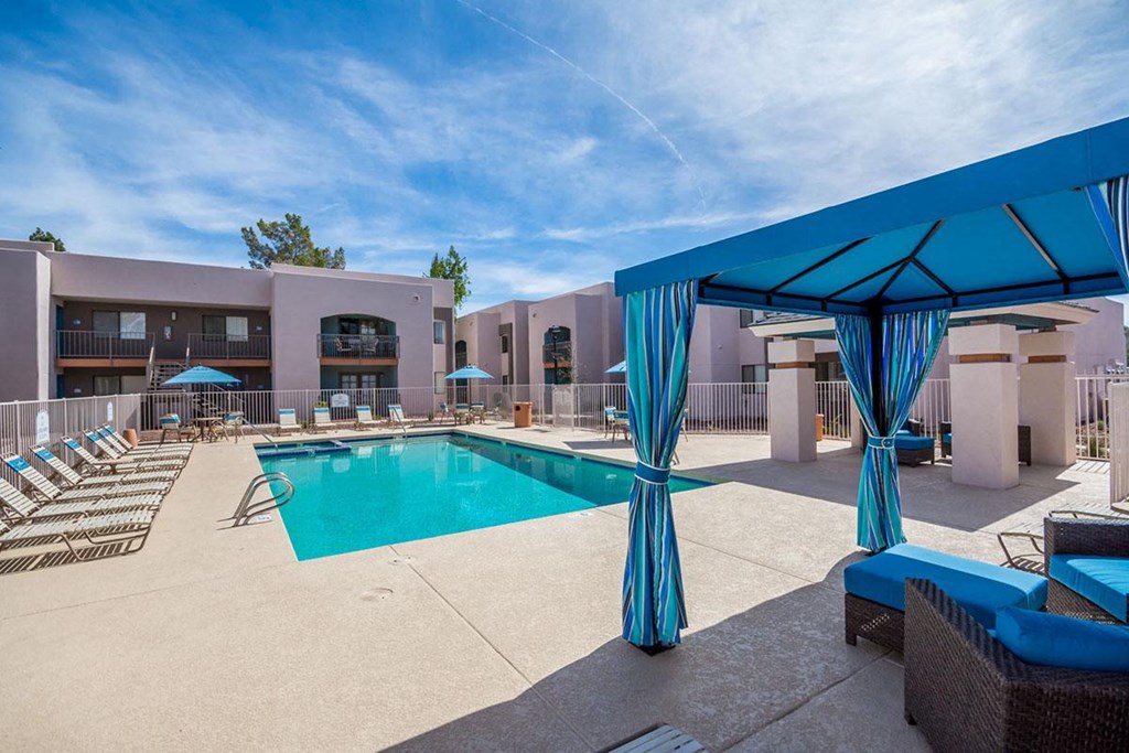 A pool area with a blue canopy and lounge chairs.