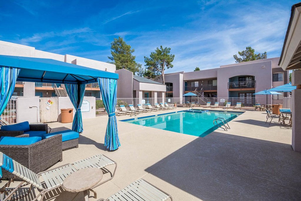 A pool area with a blue canopy and lounge chairs.