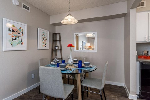 A dining room with a table set for two and a chandelier hanging from the ceiling.