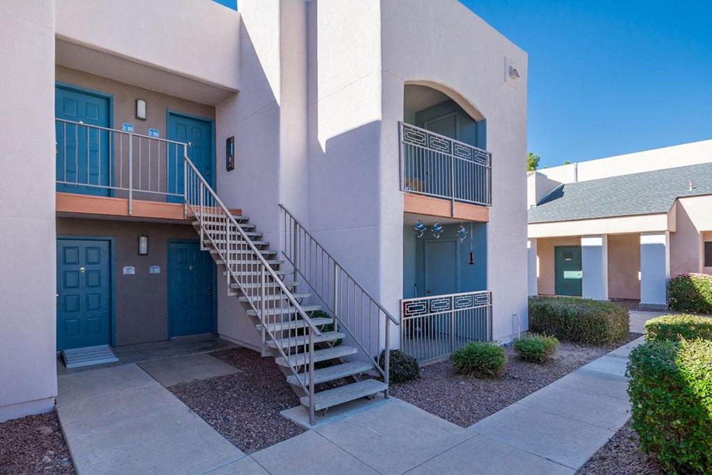 A building with a blue door and a staircase leading to a balcony.