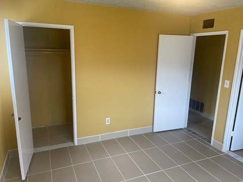A room with two open doors and tiled flooring.