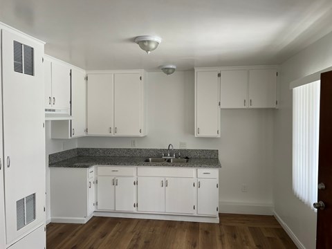 A kitchen with white cabinets and a granite countertop.