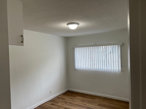 A room with a window covered by white blinds.