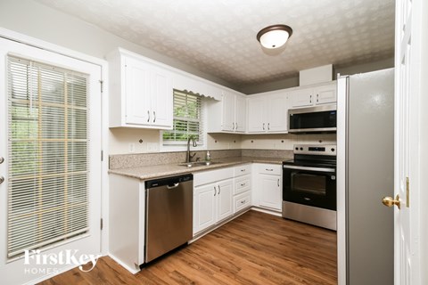A kitchen with white cabinets and a wooden floor.