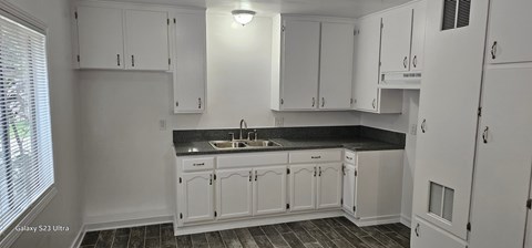 A kitchen with white cabinets and a black countertop.