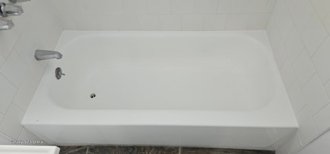 A white bathtub with a faucet and a drain.
