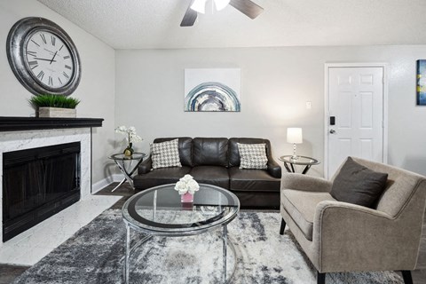 A living room with a fireplace, a couch, a chair, and a clock on the wall.