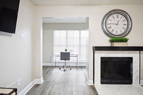 A large clock sits on top of a fireplace in a well-lit room.