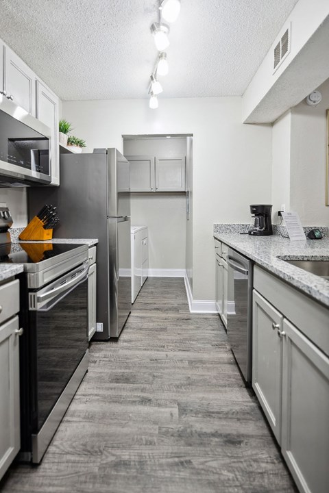 A kitchen with a refrigerator, microwave, and oven.