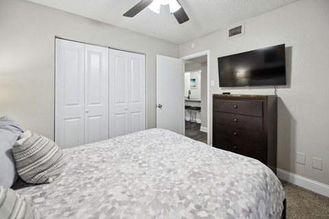 A bedroom with a bed, dresser, and television.