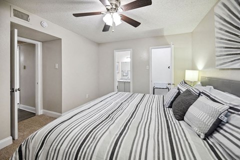 A bedroom with a bed, pillows, and a ceiling fan.