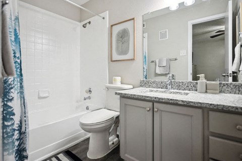 A white toilet sits in a bathroom with a white shower curtain.