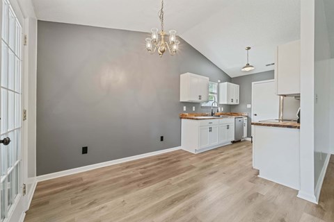 A kitchen with white cabinets and a wooden floor.
