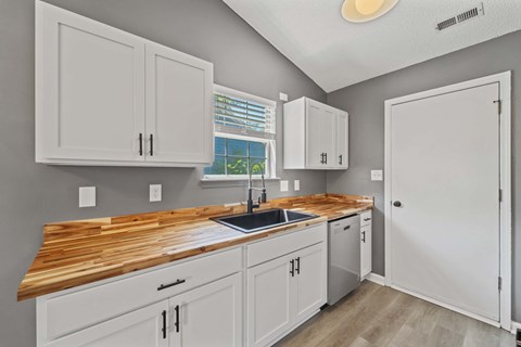 A kitchen with white cabinets and a wooden countertop.
