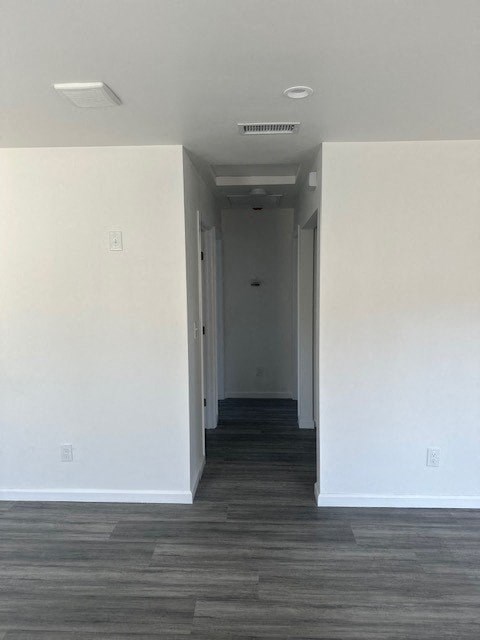 A long hallway with a light on the ceiling and a door at the end.