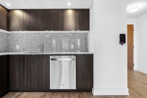 A modern kitchen with dark wood cabinets and a white dishwasher.