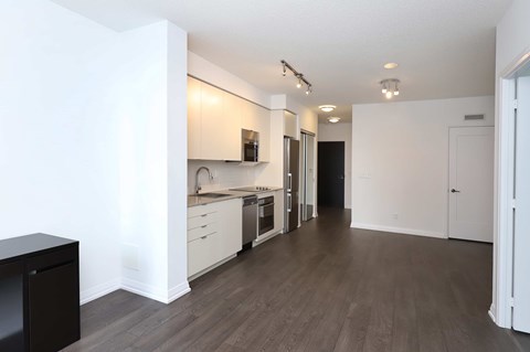 A kitchen with white cabinets and a black trash can.
