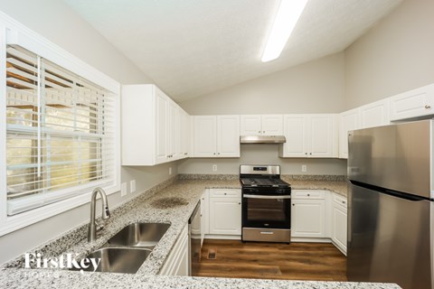 A kitchen with a granite counter top and stainless steel appliances.