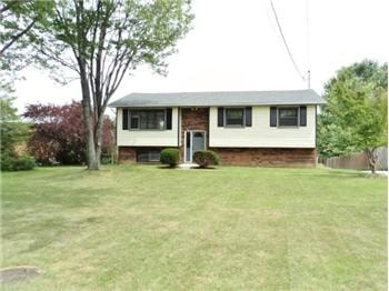 A house with a white door and windows sits in a grassy yard.