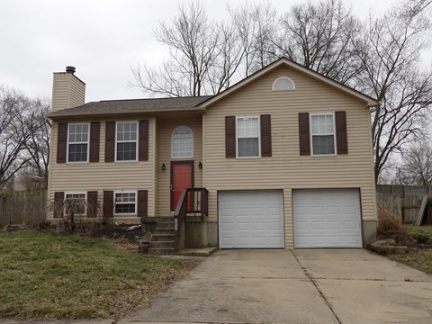 A two-story house with a red door and white garage doors.