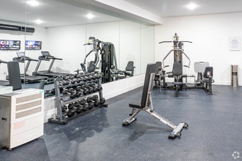 A gym with a variety of equipment including treadmills, weights, and exercise machines.
