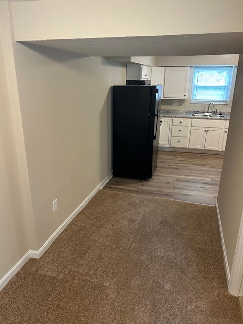 A black refrigerator in a kitchen with white cabinets.