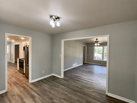 A spacious room with wood flooring and a large window.