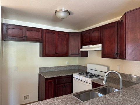 A kitchen with a stove, sink and cabinets.