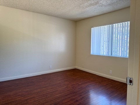 A room with wooden floors and a window with blinds.