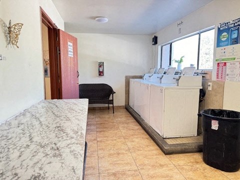 A room with a marble table, a black chair, and a white cabinet with a red door.