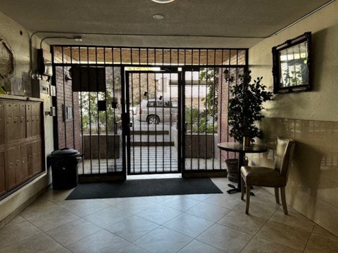 A black metal gate is closed on a white door.