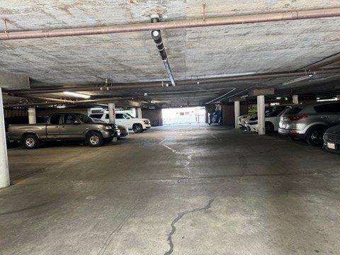 A parking garage with a few cars and a light hanging from the ceiling.