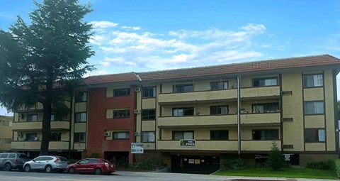 A multi-story apartment building with cars parked in front.