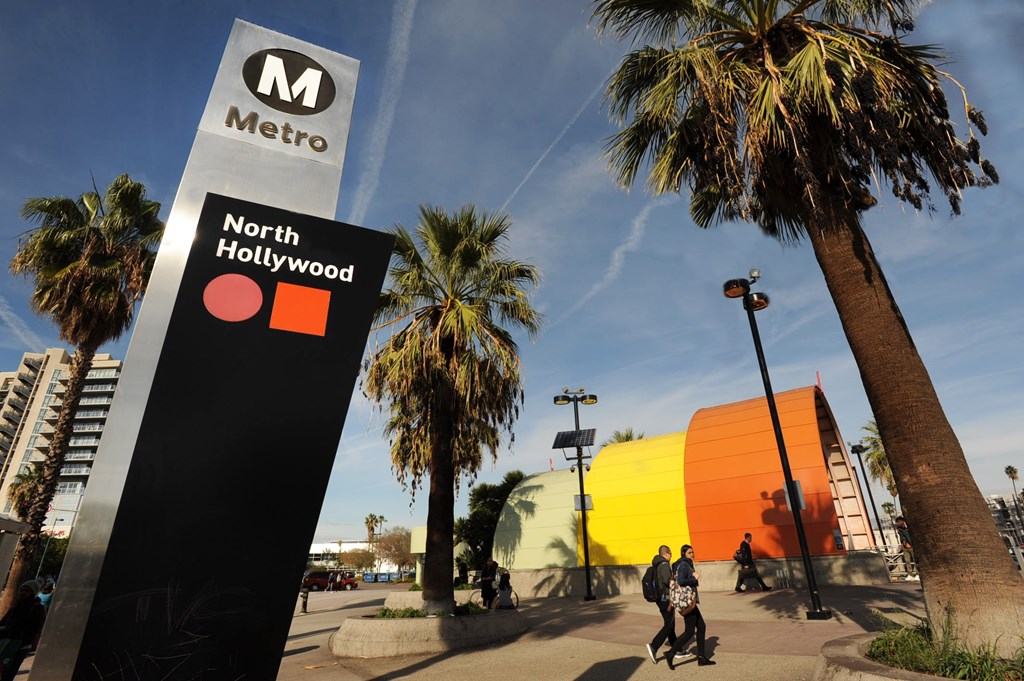 A sign for the North Hollywood Metro station is shown with a person walking in the background.