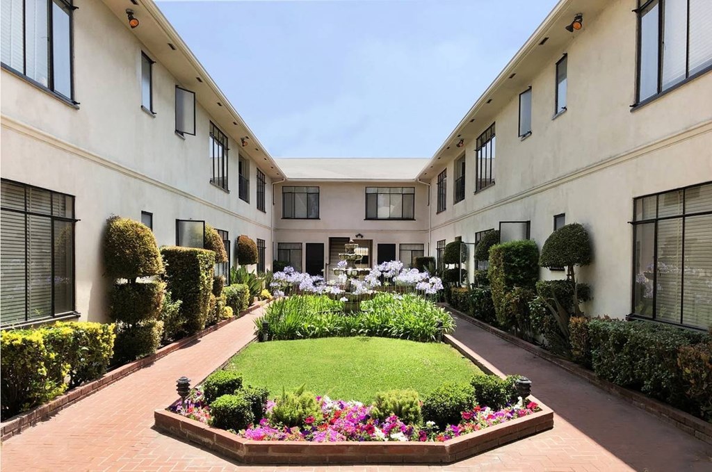 A garden in front of a building with a lawn and flowers.