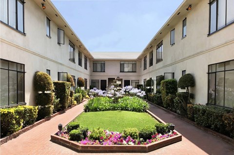 A garden in front of a building with a lawn and flowers.