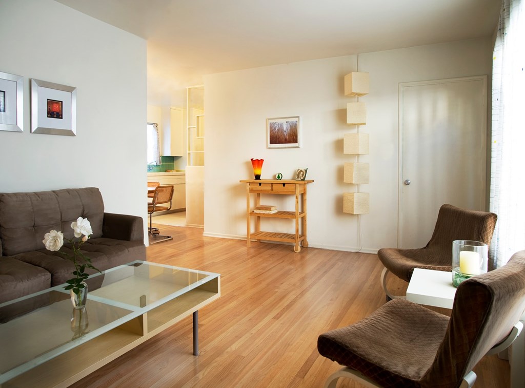 A living room with a grey couch, a glass coffee table, and a brown chair.