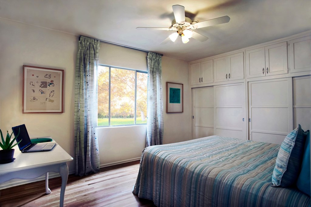 A bedroom with a bed, desk, and window.