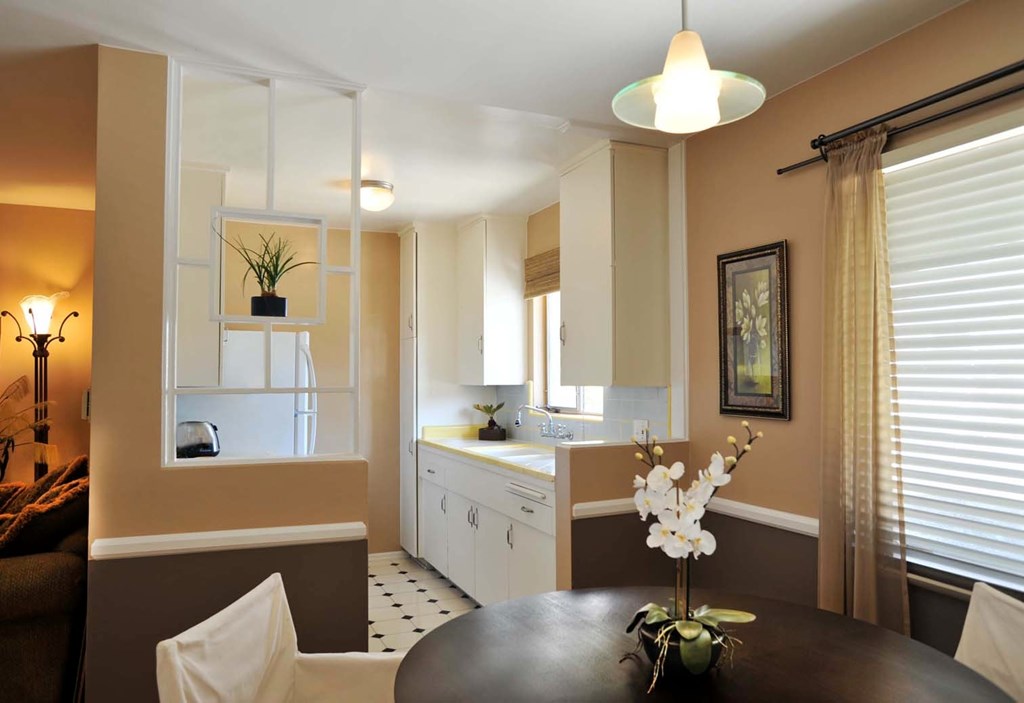 A dining room with a table set for two and a kitchen area in the background.