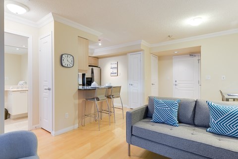 A living room with a grey couch and a white desk with a computer.