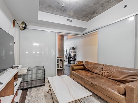 A living room with a brown leather couch and a white rug.