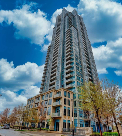 A tall building with a blue sky and clouds in the background.