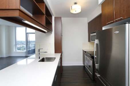 A modern kitchen with dark wood cabinets and stainless steel appliances.