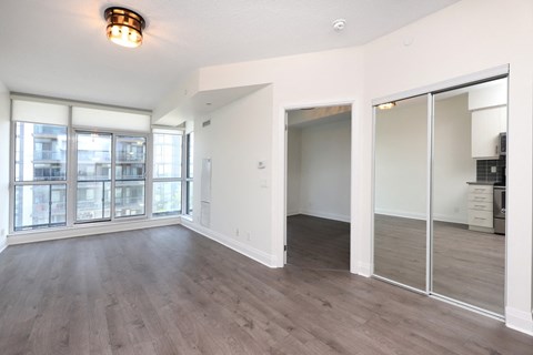 A spacious room with a large window and wooden flooring.